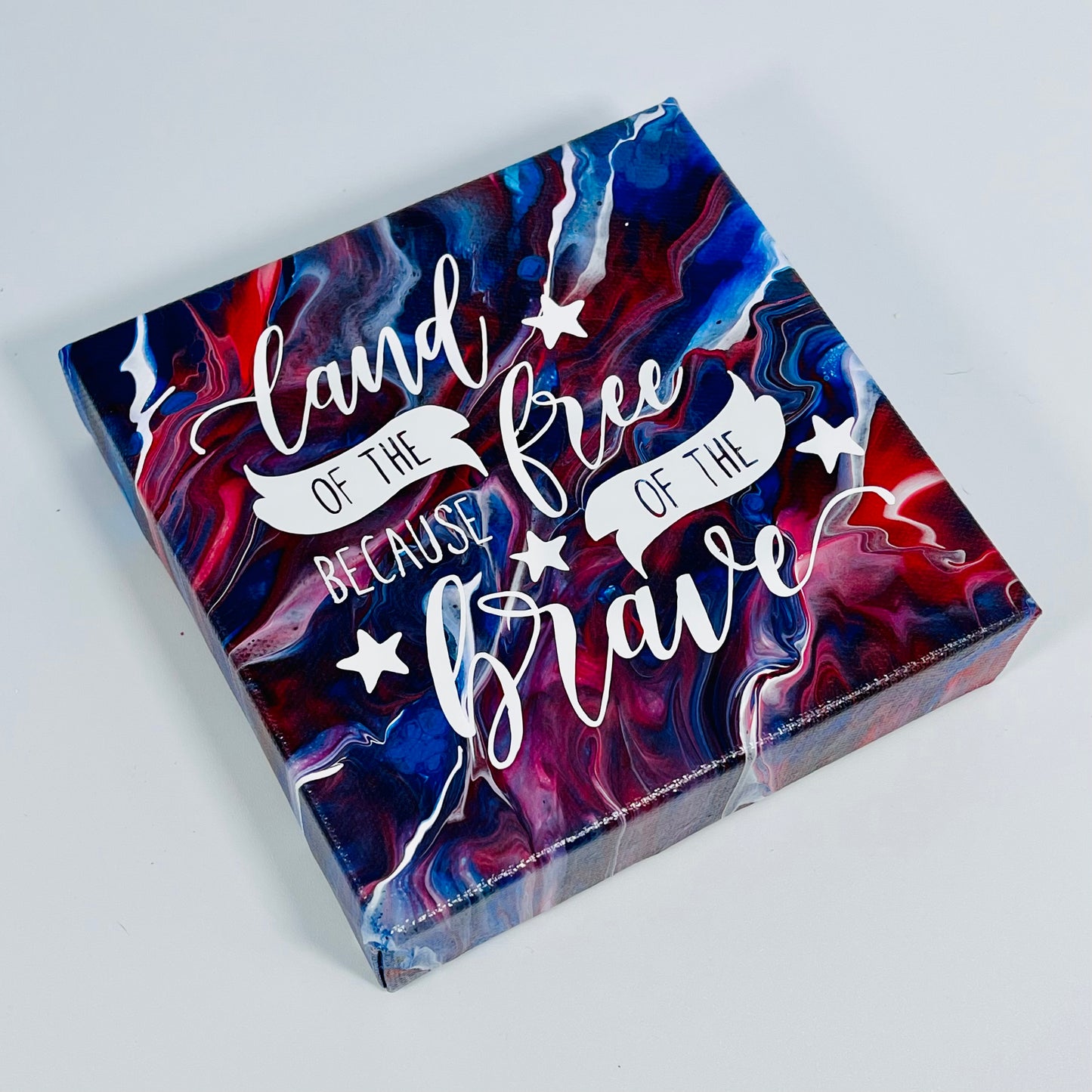 The Honor Freedom Block. A red, white, and blue hand painted painting that says 'land of the free because of the brave'