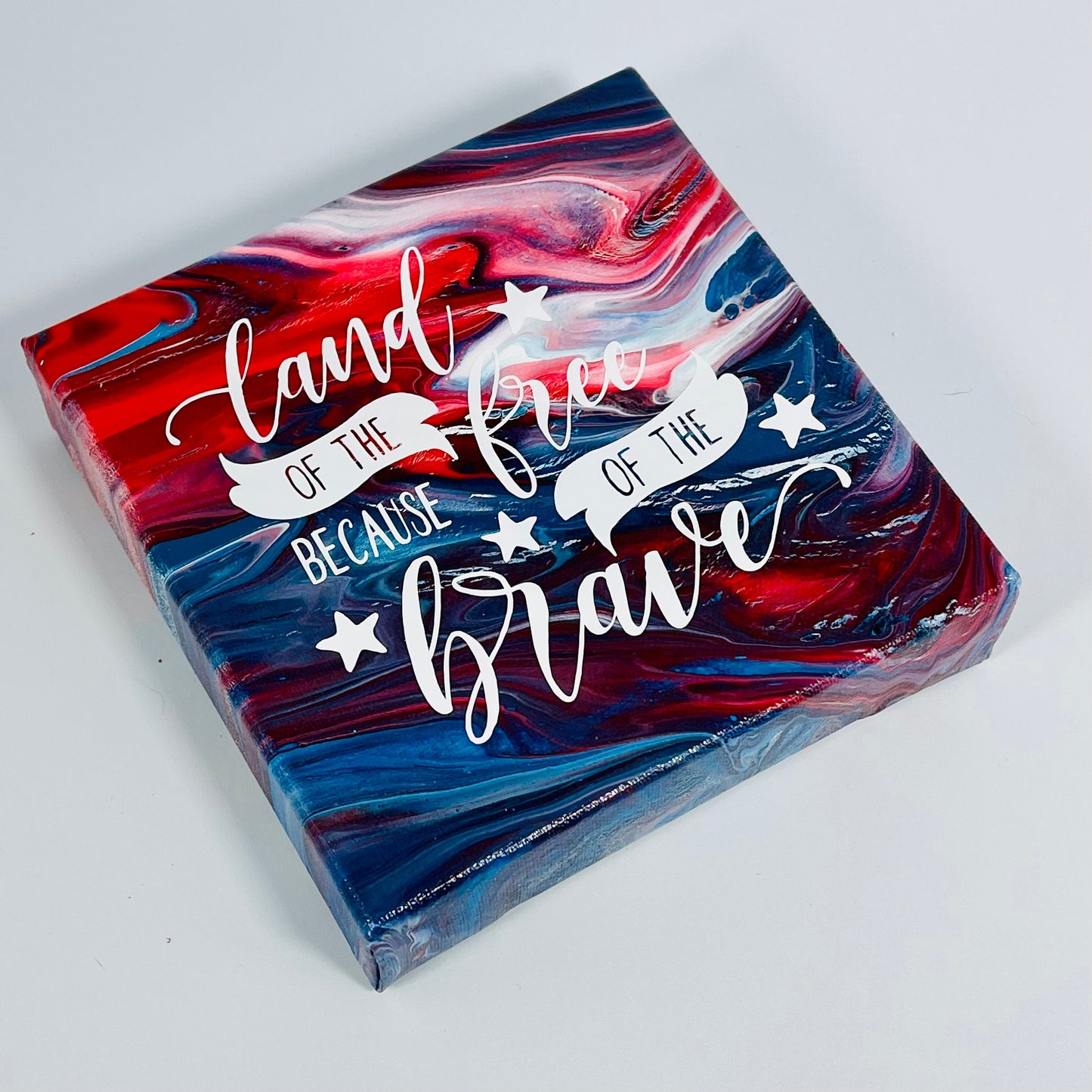 The Anthem Freedom Block. A red, white, and blue hand painted painting that says 'land of the free because of the brave'