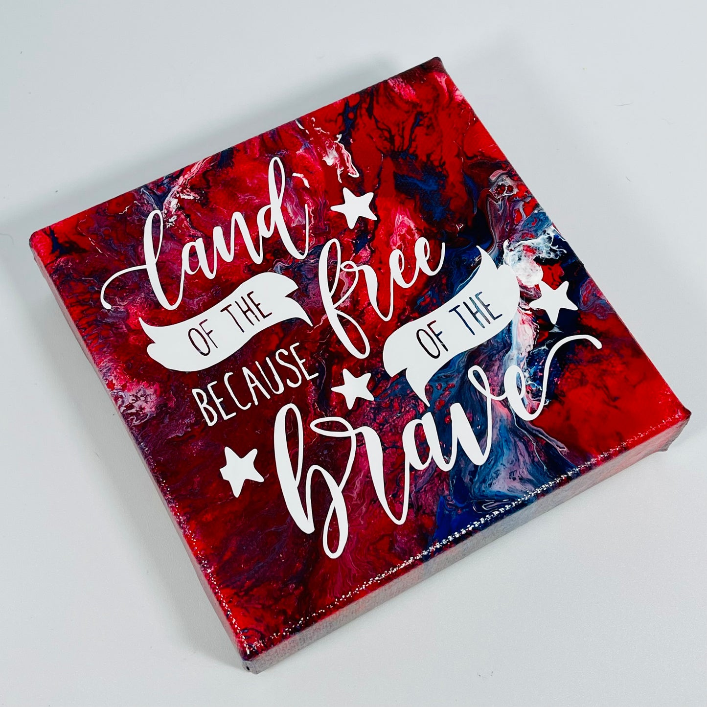 The Scout Freedom Block. A red, white, and blue hand painted painting that says 'land of the free because of the brave'