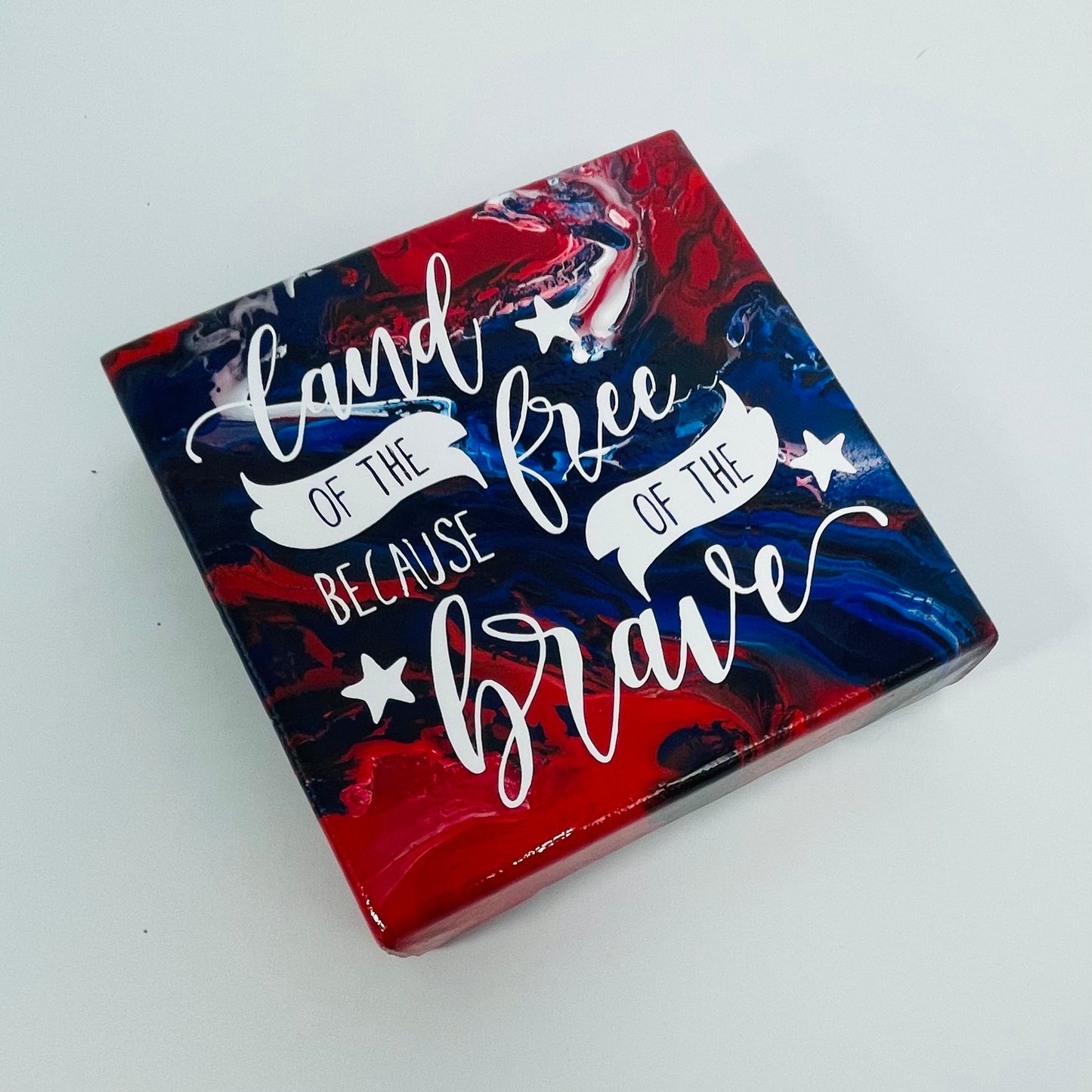 The Sergeant Freedom Block. A red, white, and blue hand painted painting that says 'land of the free because of the brave'