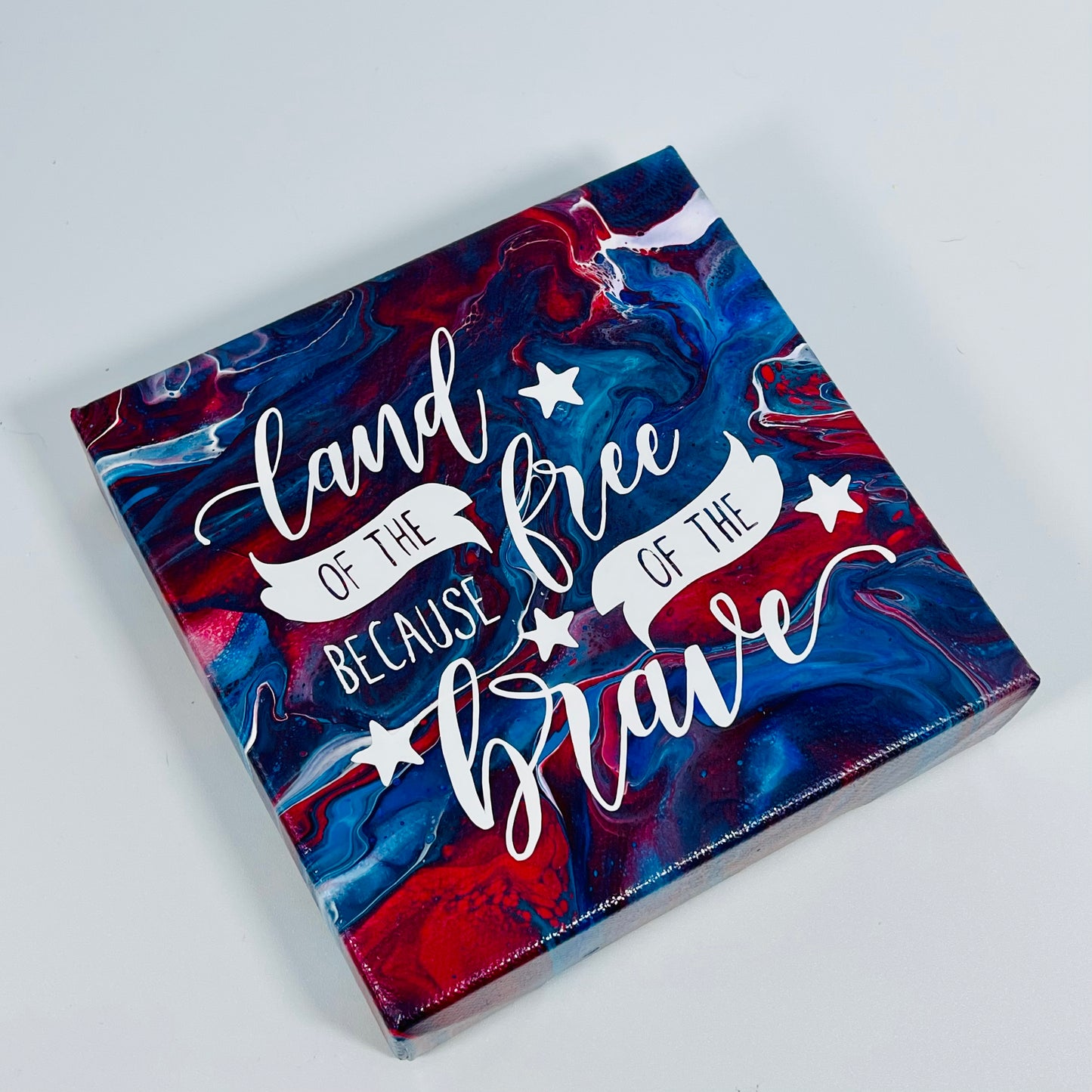 The Soldier Freedom Block. A red, white, and blue hand painted painting that says 'land of the free because of the brave'