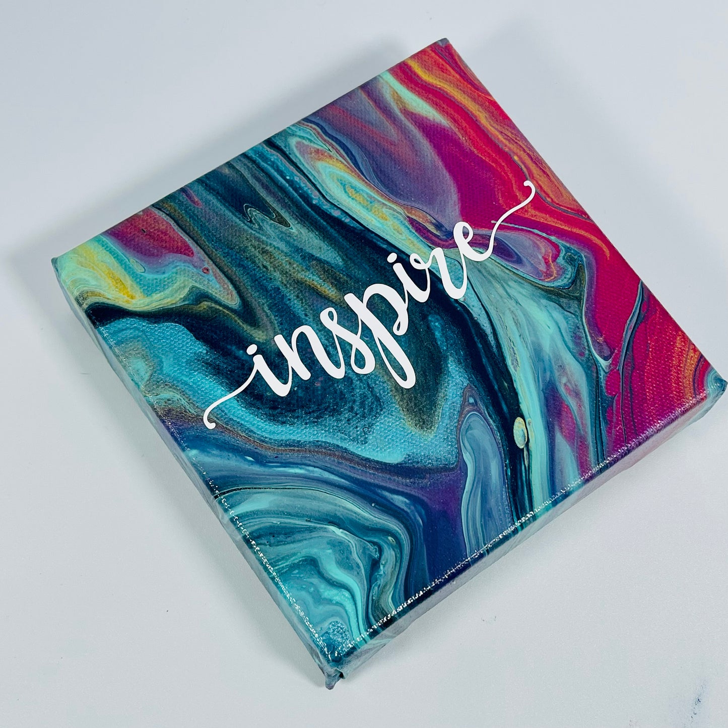 The Dali Inspire Block. A colorful hand painted painting that says 'Inpire'